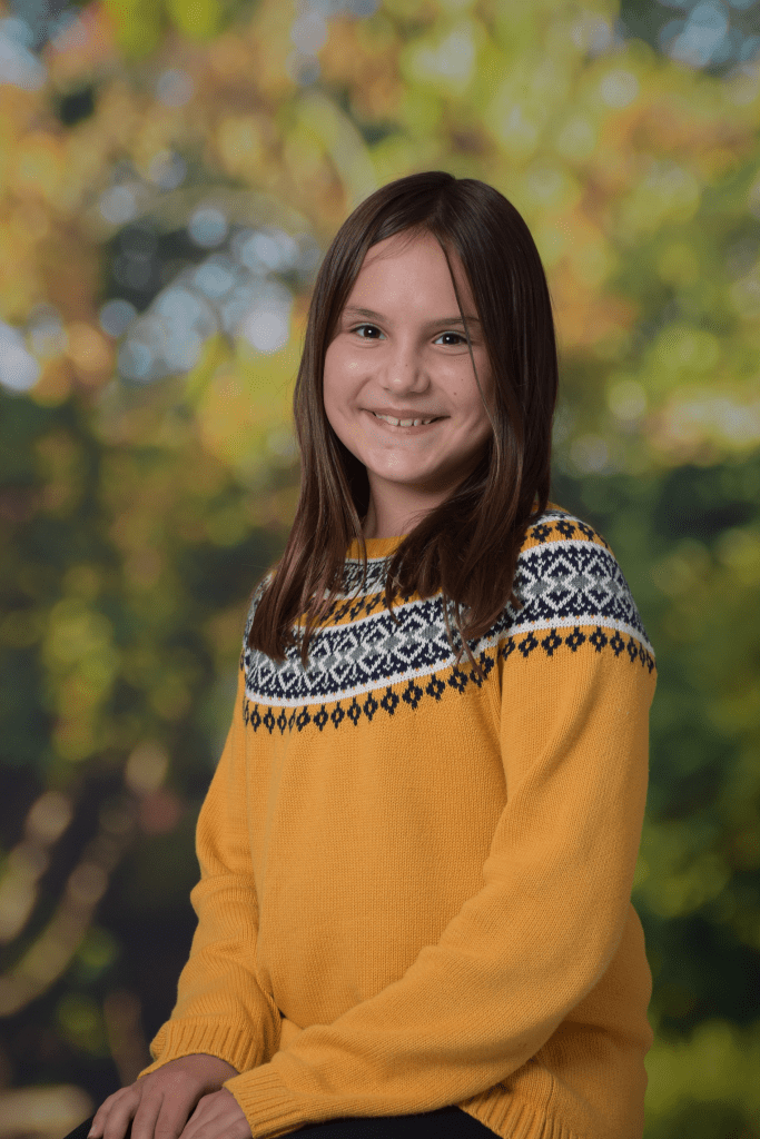 Photograph of girl sitting with a blurred foliadge background